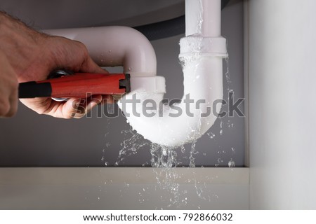 Close-up Of Male Plumber Fixing White Sink Pipe With Adjustable Wrench