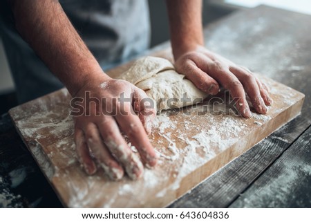 Baker hands kneading the dough with flour