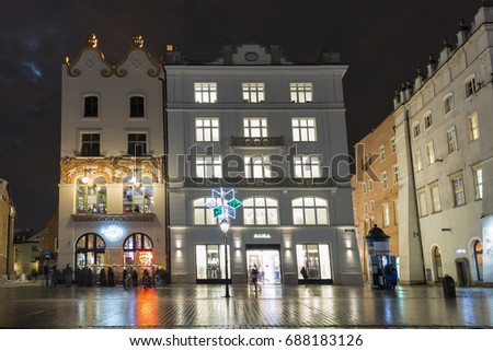 KRAKOW, POLAND - JANUARY 12, 2017: People walk along Hard Rock Cafe and Zara store on Main Market square in old town at night. Krakow is the second largest and one of the oldest cities in Poland.