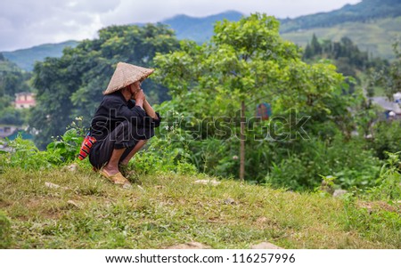 Asian man with conical hat looking upwards sideview