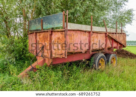 Neglected Old And Rusty Farm Trailer Parked In The Grass Next To A Field Neglected Old And Rusty Farm Trailer Parked In The Grass Next To A Field