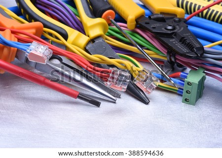 Tools for electrician and cables on grey metal surface