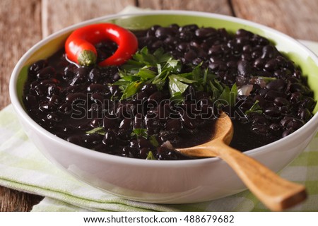thick soup of black bean with chilli peppers close up in a bowl on the table. horizontal