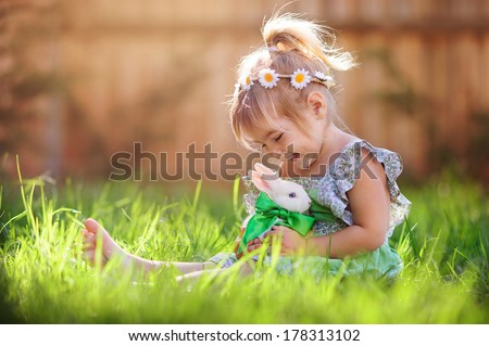 Cute little girl with a bunny rabbit has a easter at green grass background - stock photo