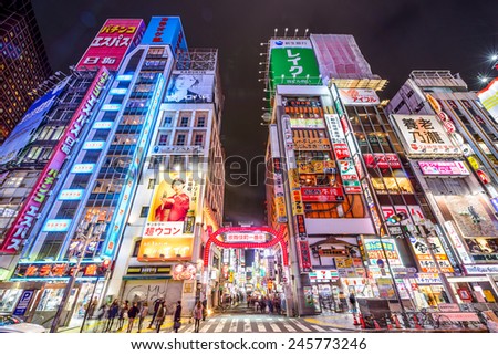 TOKYO, JAPAN - MARCH 14, 2014: Pedestrians walk below signs densely ...