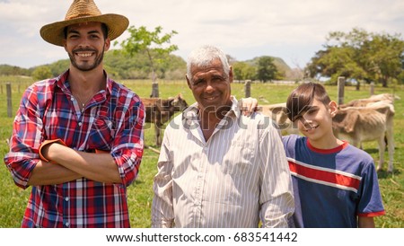 Everyday life for farmers with cows in the countryside. Peasants work in Latin America with livestock in family country ranch. Portrait of happy grandfather, dad and child smiling.