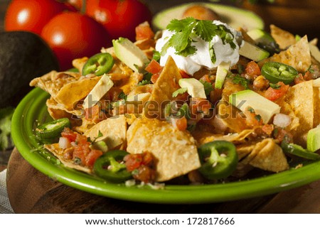 Homemade Unhealthy Nachos with Cheese, Sour Cream, and Vegetables - stock photo