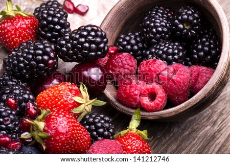 tasty summer fruits on a wooden table. Cherry, Blue berries, strawberry, raspberries, Blackberries, pomegranate