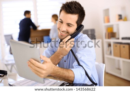 Cheerful man in office answering the phone