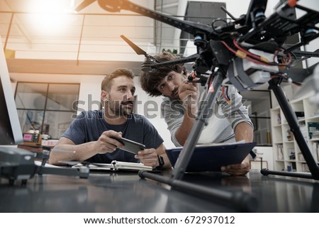 Engineer and technician working together on drone in office