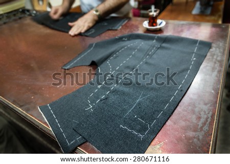 A tailor's work table with cloth for a jacket cut and marked up for sewing. (SELECTIVE FOCUS)