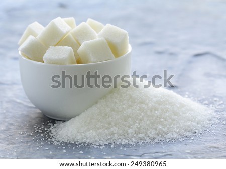 white granulated sugar and refined sugar on a gray background