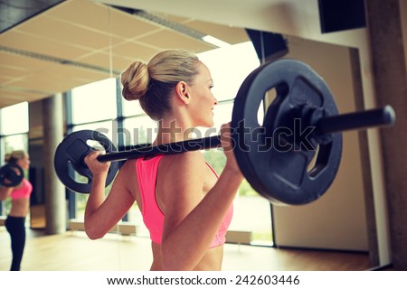 fitness, sport, powerlifting and people concept - sporty woman exercising with barbell in gym