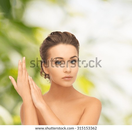 health and beauty concept - face and hands of beautiful woman with updo