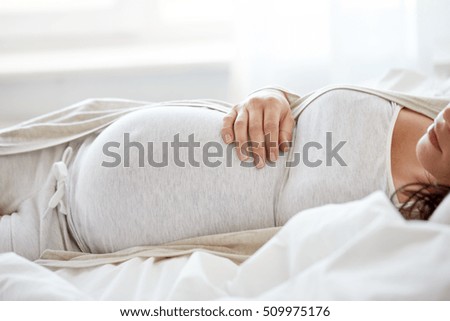 pregnancy, rest, people and expectation concept - pregnant woman sleeping in bed at home