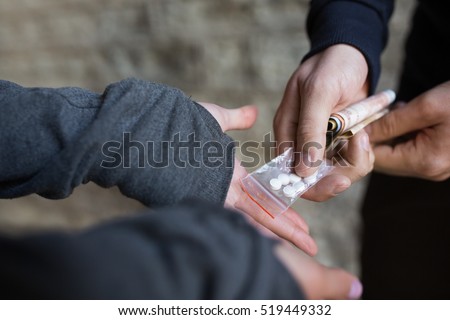 drug trafficking, crime, addiction and sale concept - close up of addict with money buying dose from dealer on street