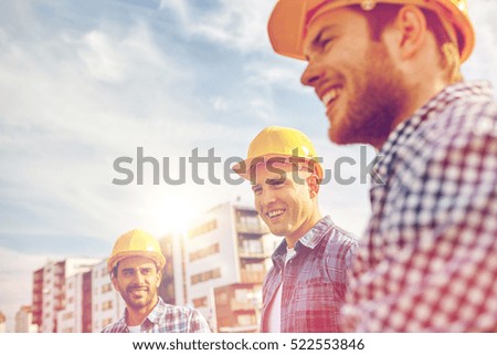 business, building, teamwork and people concept - group of smiling builders in hardhats at construction site