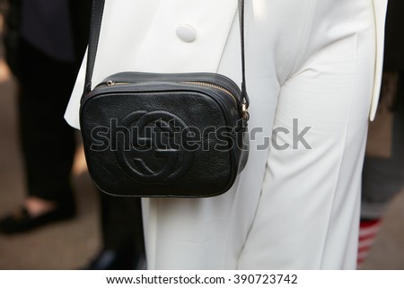MILAN - FEBRUARY 25: Woman poses for photographers with black leather Gucci bag and white suit before Emilio Pucci fashion show, Milan Fashion Week Day 2 street style on February 25, 2016 in Milan.