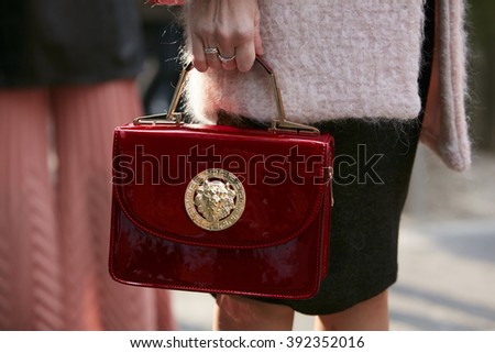 MILAN - FEBRUARY 26: Woman poses for photographers with dark red Versace bag before Emporio Armani fashion show, Milan Fashion Week Day 3 street style on February 26, 2016 in Milan.