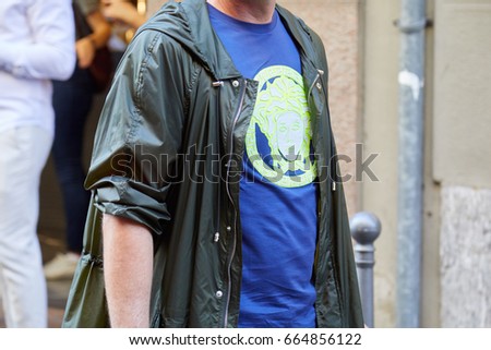 MILAN - JUNE 17: Man with green Medusa logo on blue t-shirt before Versace fashion show, Milan Fashion Week street style on June 17, 2017 in Milan.