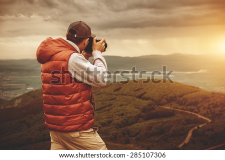 Photographer is taking a picture of sunset in mountains