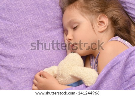 cute little girl sleeping with a toy in her bed