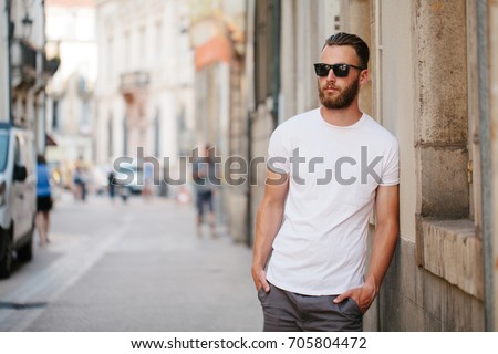 Hipster handsome male model with beard wearing white blank t-shirt with space for your logo or design in casual urban style
