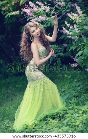 stock photo beautiful redhead girl with long wavy curls in a beautiful green dress walk in the park among the 433575916