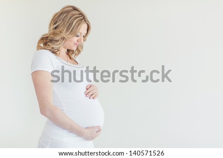 pregnant woman caressing her belly over white background