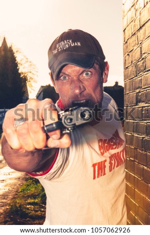 Aalst, Belgium - March 11, 2012: professional stuntman acting in a film holding a gun