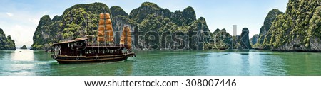 panorama view on sea gulf Halong bay with ship surrounded with high mountains, direct rocks with green trees and blue sky and clouds at sunny day,Southeast Asia, Ha Long Bay, Vietnam