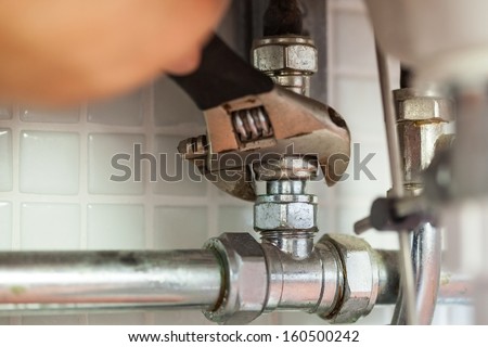 Close up of hand repairing pipes with wrench