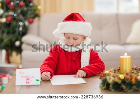 Festive little boy writing wish list at home in the living room
