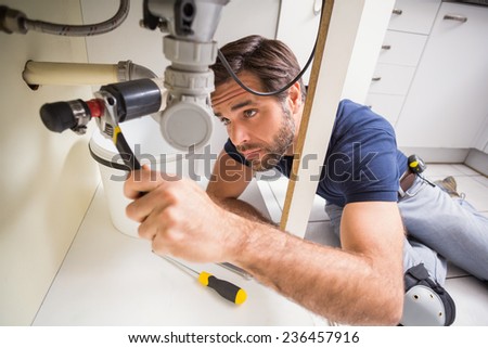 Plumber fixing under the sink in the kitchen