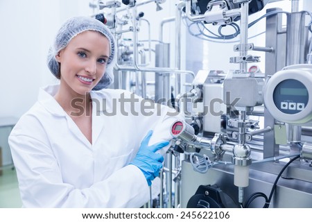 Smiling scientist leaning against gauge in the factory