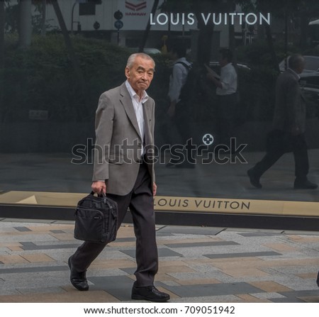 TOKYO, JAPAN - SEPTEMBER 1ST, 2017. Japanese white collar workers or salaryman walking in front of Louis Vuitton outlet at Tokyo station.