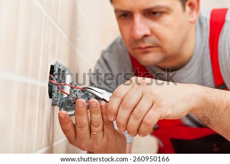 Electrician working on electrical wall fixture - inserting the wires, closeup