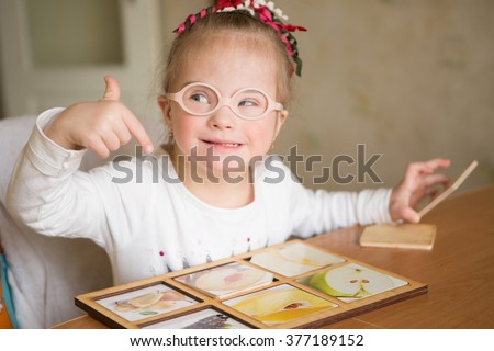stock-photo-smart-girl-with-down-syndrome-collects-puzzles-377189152.jpg