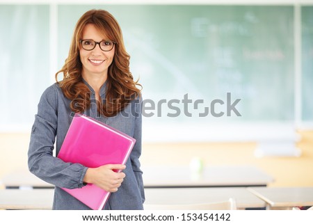 Smiling teacher standing in front of blackboard