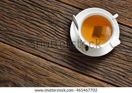 Top view of a cup of tea with tea bag on wooden table