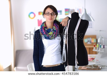 Smiling fashion designer standing near mannequin in office