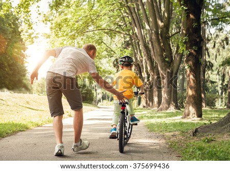 Father learn his little son to ride a bicycle