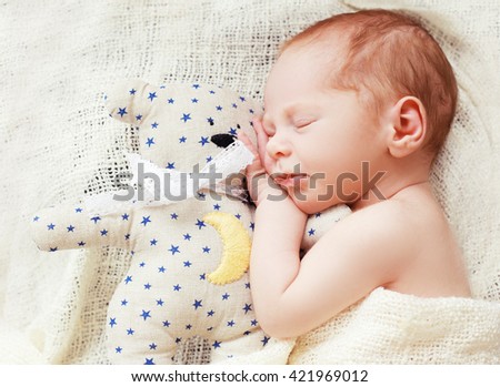 Baby sleeping with her teddy bear. New born relax in a white bedroom. Family at home. Love