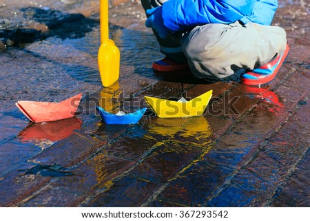 child playing with paper boats in spring water