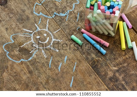 Child's drawings and colored chalk on wooden background