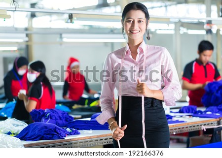 Female Indonesian tailor, dressmaker or designer standing proudly in an Asian textile factory, it is her workplace