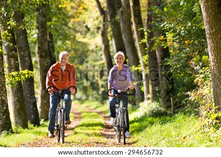 Senior Man and woman exercising with bicycles outdoors, they are a couple