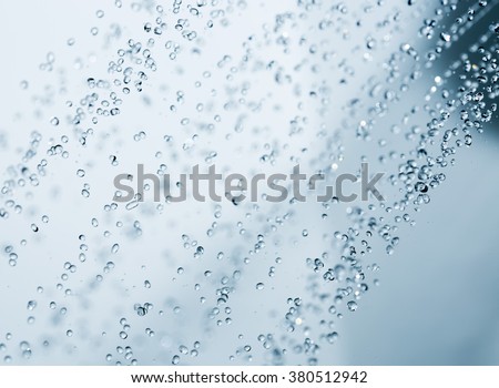 Closeup of a shower head with sprinkling water, blue toned photo.