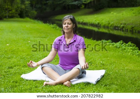 https://thumb9.shutterstock.com/display_pic_with_logo/868264/207822982/stock-photo-older-woman-in-park-by-a-river-doing-yoga-207822982.jpg