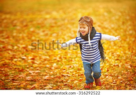 happy child playing pilot aviator and dreams outdoors in autumn